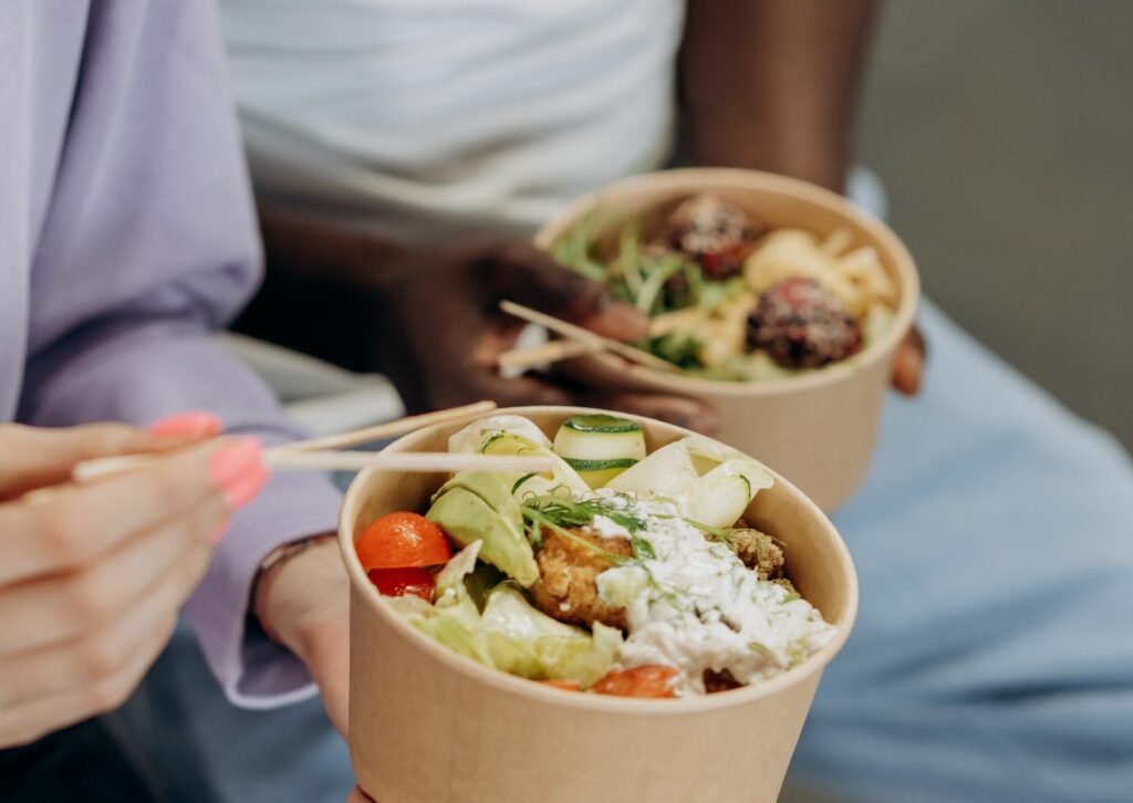 white lady and black men eating poke bowls with a chopstick