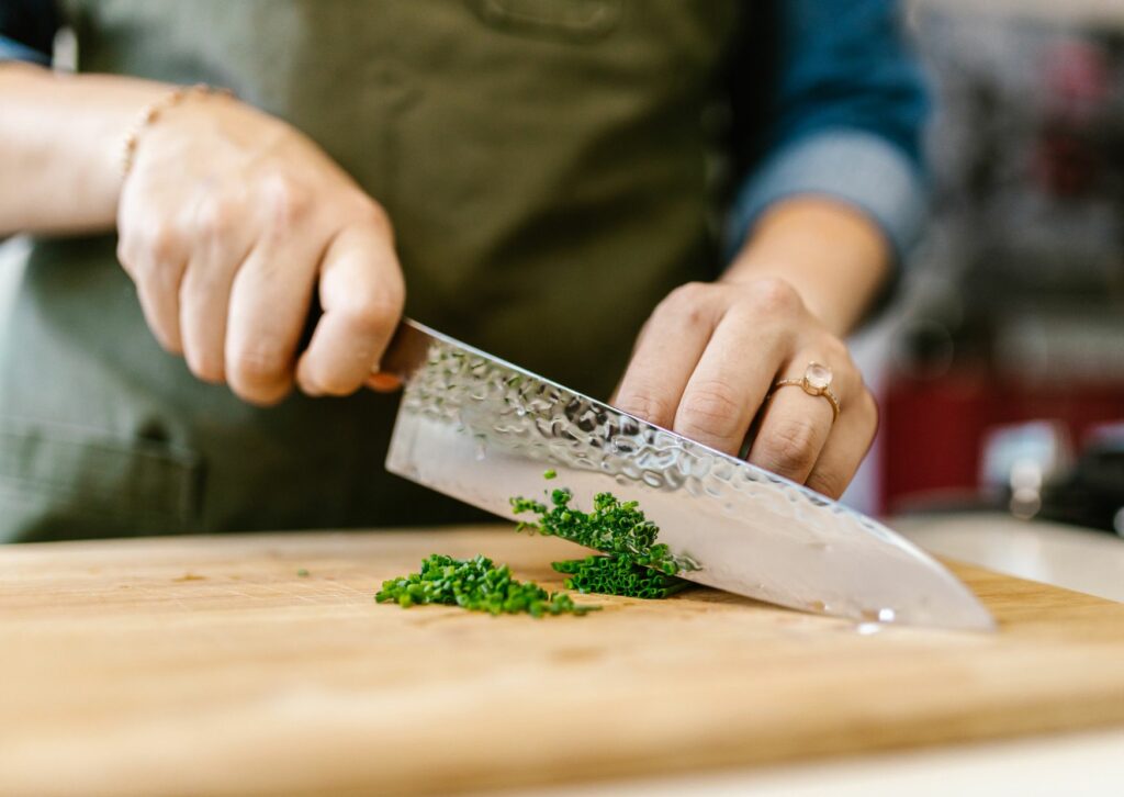 woman cutting green onions on cutting board wearing a ring